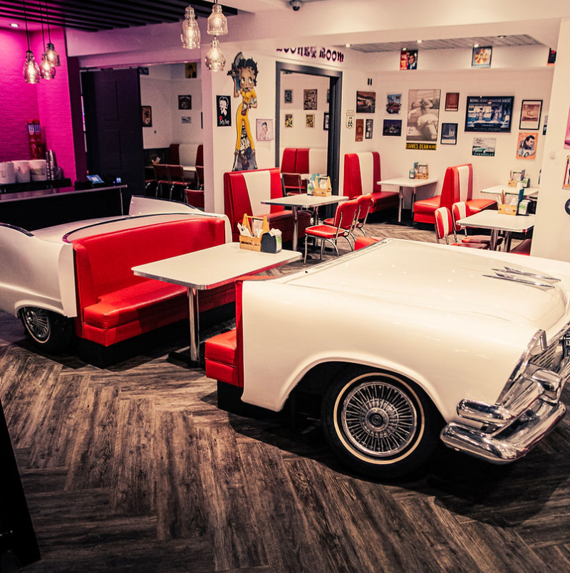A retro diner featuring a white and red car-shaped booth with classic decor and bright seating, evoking a nostalgic atmosphere A retro diner featuring a white and red car-shaped booth with classic decor and bright seating, evoking a nostalgic atmosphere