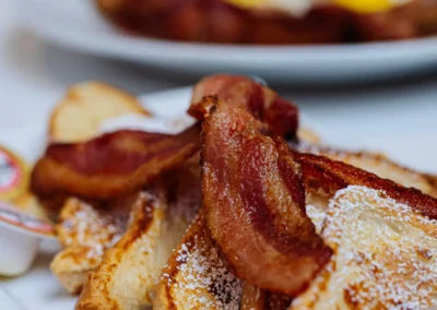 Close-up of French toast with powdered sugar and bacon